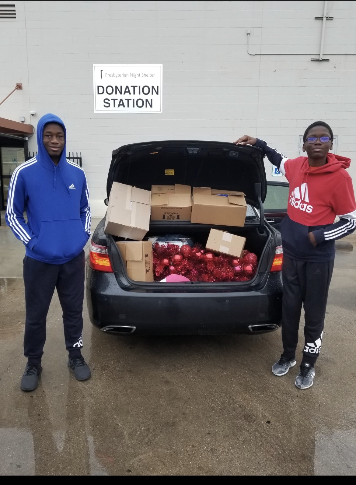 Tyrone Njelezek and brother pose with donations outside car.